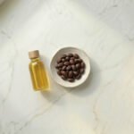 Jojoba yağı ve Simmondsia chinensis tohumları — beyaz mermer üzeri