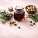 Ardıç katranı ve Juniperus oxycedrus dalı — koyu amber katran ve mavi ardıç meyveleri